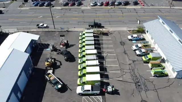 An aerial view of the Burke yard with about ten lime-green Burke Plumbing trucks lined up