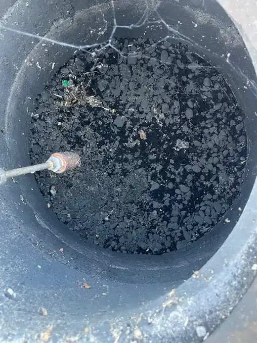 A jetting nozzle working a catch basin choked with debris