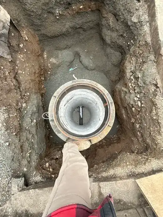 An excavated pit with a new cleanout riser standing in the trench