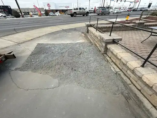 A fresh concrete patch in a commercial walkway after a line repair