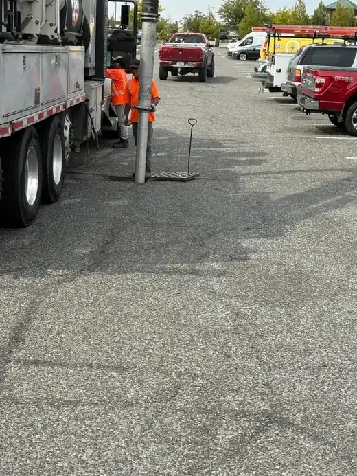A Burke jetting truck and crew working a parking-lot storm drain